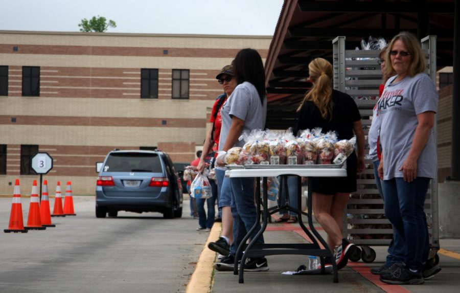 Conroe ISD employees waiting for the next car to go through with table full of meals.