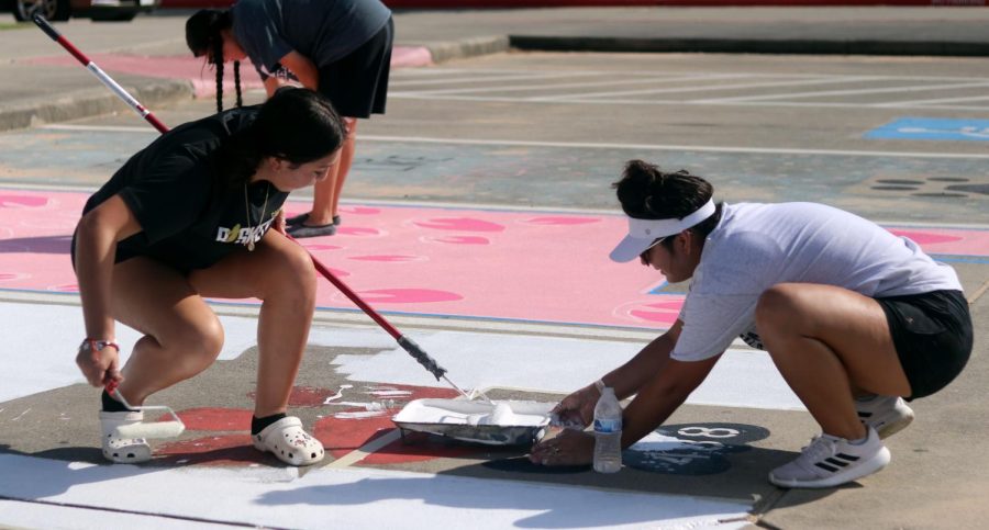 I GOT YOU. Senior Isabel Iracheta holds on to the painting tray while her sister, sophomore Alma Iracheta helps her paint her senior parking spot.The class of 2023 seniors had the opportunity to paint their parking spots with help of their peers on Sept,17-18, 2022. They were in the parking lot as early as 8 a.m. and had the chance to come back and finish the following day.

