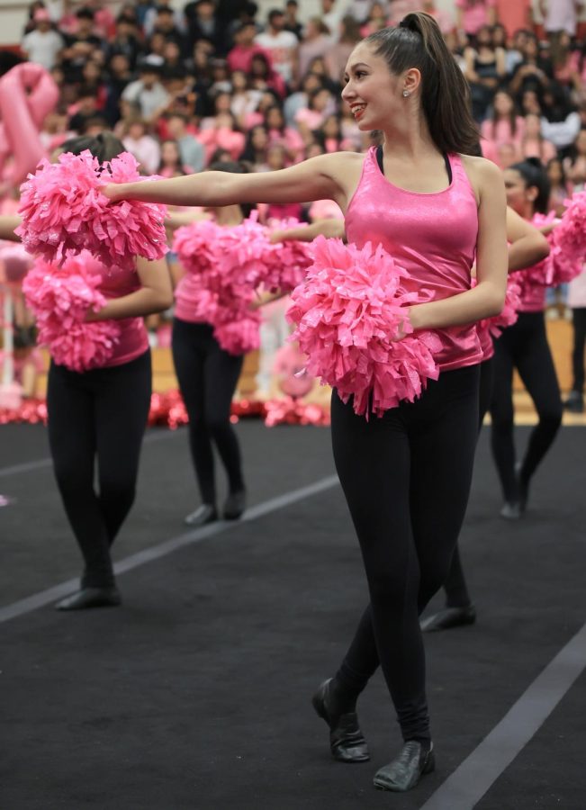 SMILE. Junior Isabella May smiles wide while she holds her pink pom poms tightly while performing in the gym for the pink out pep rally on October 14, 2022. 