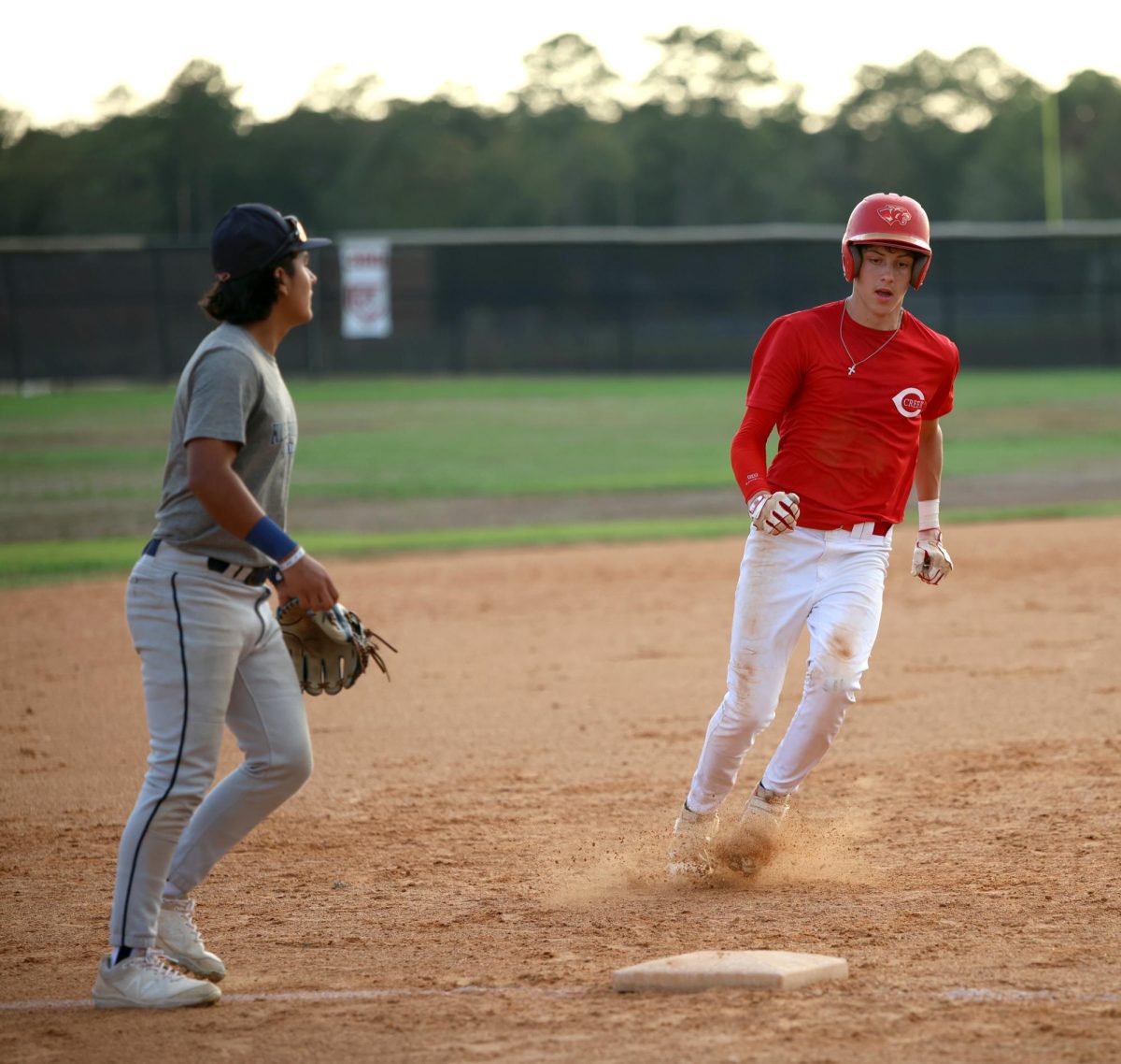 CHASE THE BAG. Junior Derek Darkenwald runs to 3rd base as the ball is out in play toward the left field on Sept. 6, 2023 at Caney Creek High School. Following the run to 3rd base, Darkenwald managed to complete the run to home base, scoring a point for his team. “We were down 5-3 at the top of the 6th inning,” Darkenwald said. “The first thing I thought in my mind was ‘I have to score and put points on the board,’ I ran as fast as I could and I eventually scored.”