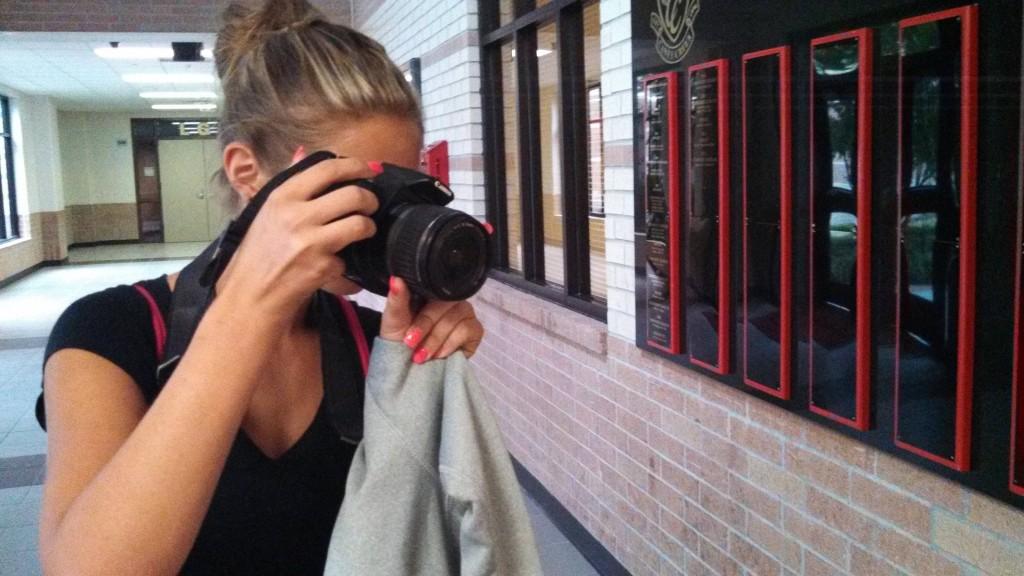 Kaitlen Kennedy uses a camera to take a photo of Pettey the Panther in front of the main office