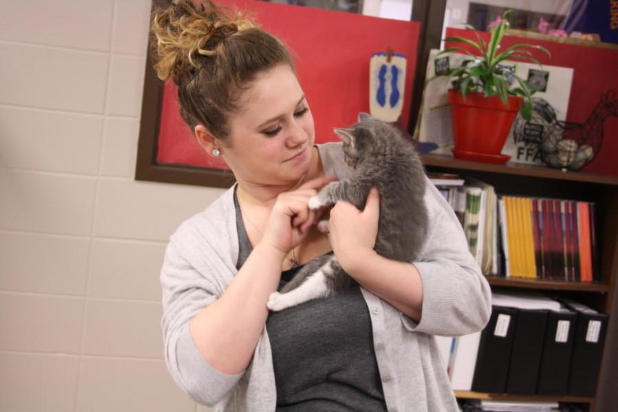 Senior Alyssa  Walulik holds a kitten close to her chest.