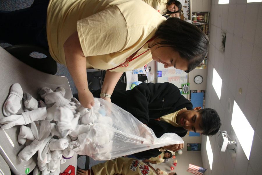 CARING. Sarah Dudley, StuCo co-adviser, and junior Ivan Sanchez, president of StuCo, empty out a donated bag of socks