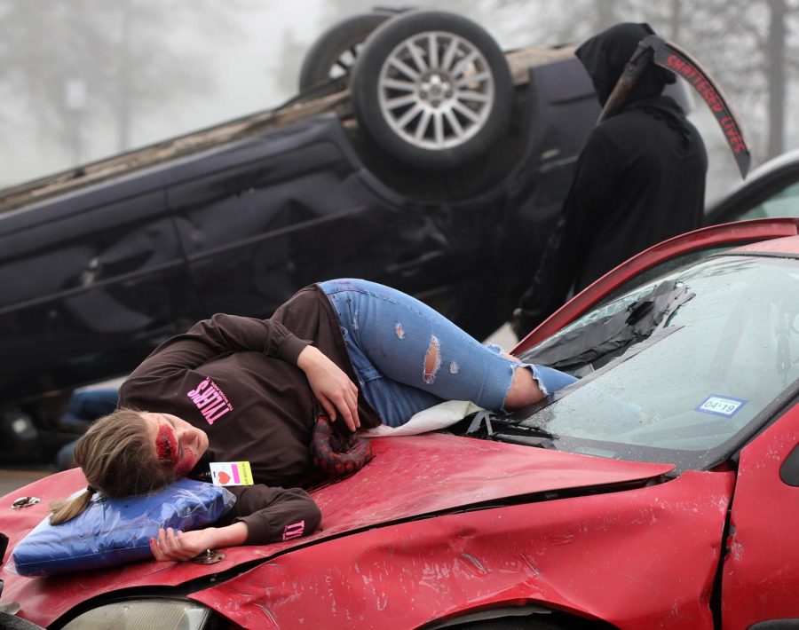 Senior Katelyn Finley lies across the hood of a vehicle after being thrown through the windshield during a simulated car wreck as part of the Shattered Lives program Wednesday, Feb. 27, 2019, at Caney Creek High School. 
