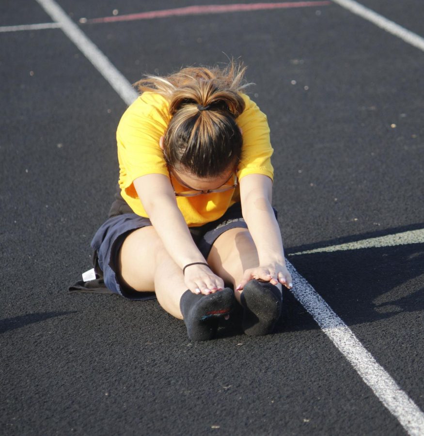 Crystal Sione is stretching on the track field before a JROTC practice