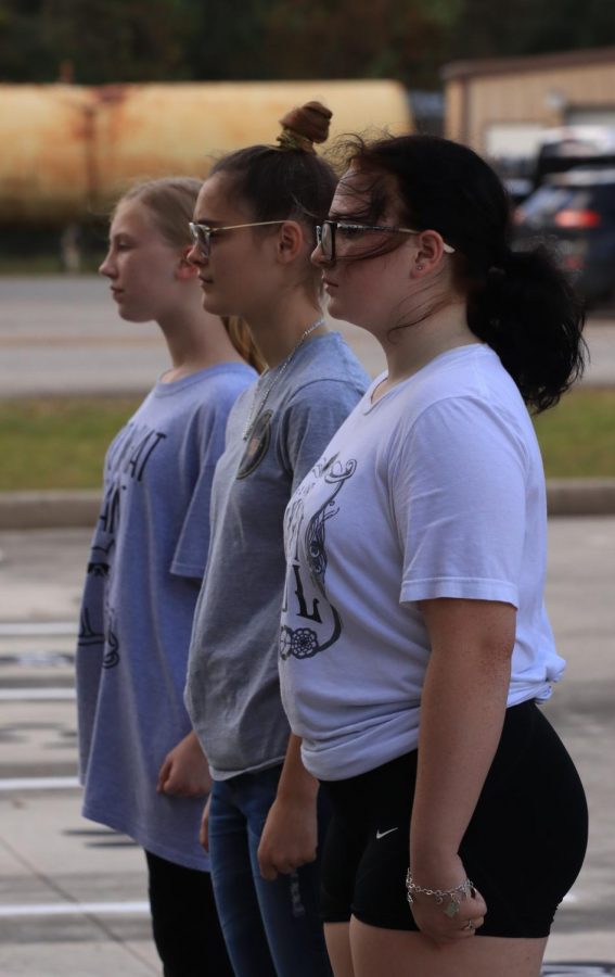 ALIGNMENT: Cali Bates (12), Summer Williams (11), and Abigail Weidner (9) all standing at attention during drill practice while perfectly aligned.