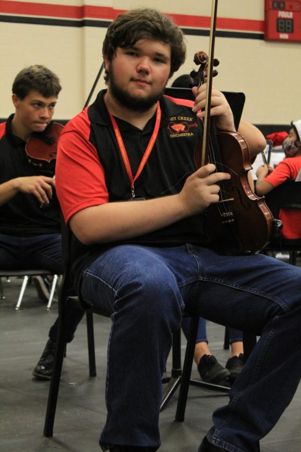 Colby Seitze is posing for the camera with his violin before the orchestra concert begins 