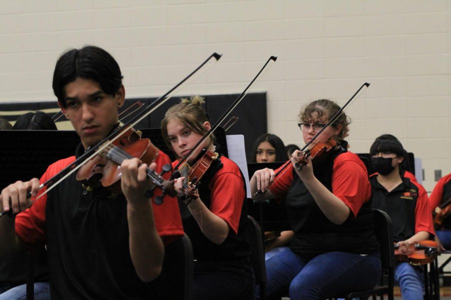 Sebastion Flores, Breanna cullens, and Amaya SIms are in the middle of performance in the orchestra concert 