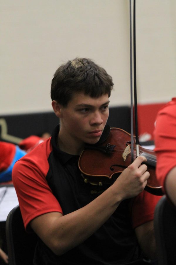 Jostin Segura is playing the violin in the middle of a heated performance in the orchestra concert.