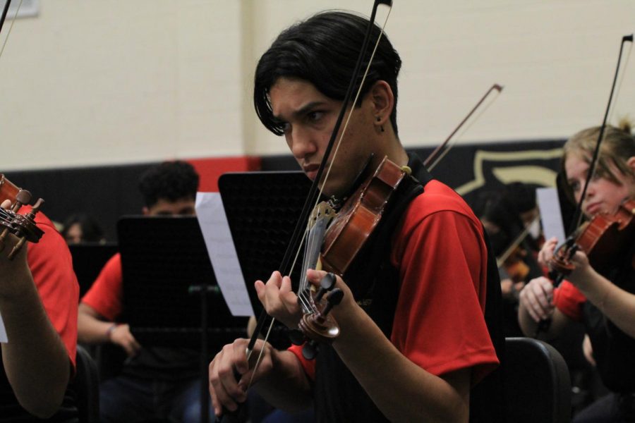 Sebastion Flores is concentrating  on his music  notes while playing  in the orchestra concert