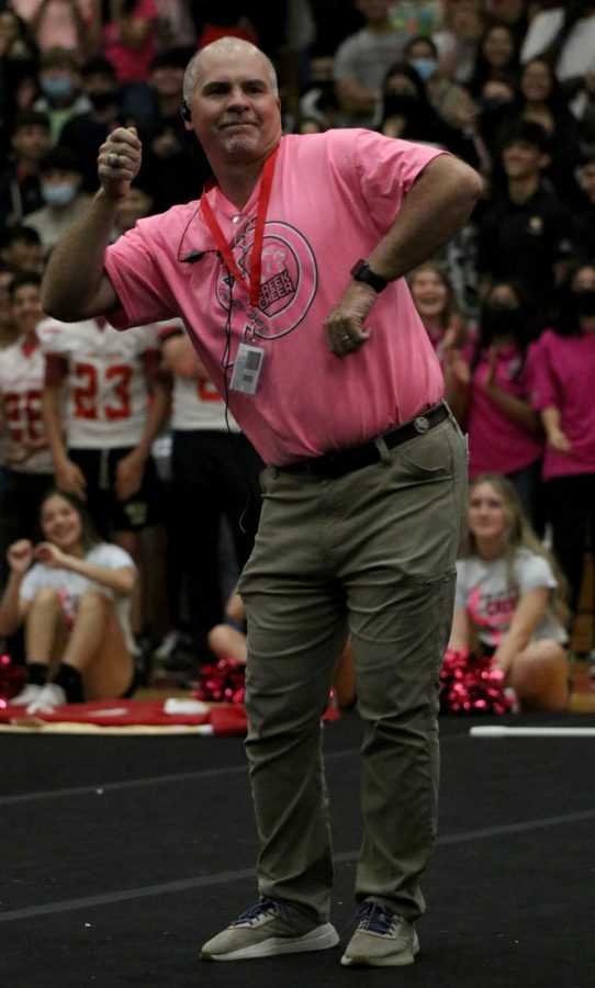 Mr. Milam is peforming in the pep rally . He is peroming a Tik Tok dance in front of everybody in the pep rally