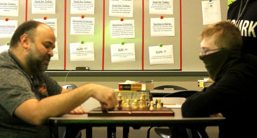 Brandon Dietrich (English teacher) is going up against Jerimiah Reno (9th).Brandon is currently moving his piece to counter jerimiahs current move while other students are spectating in the background