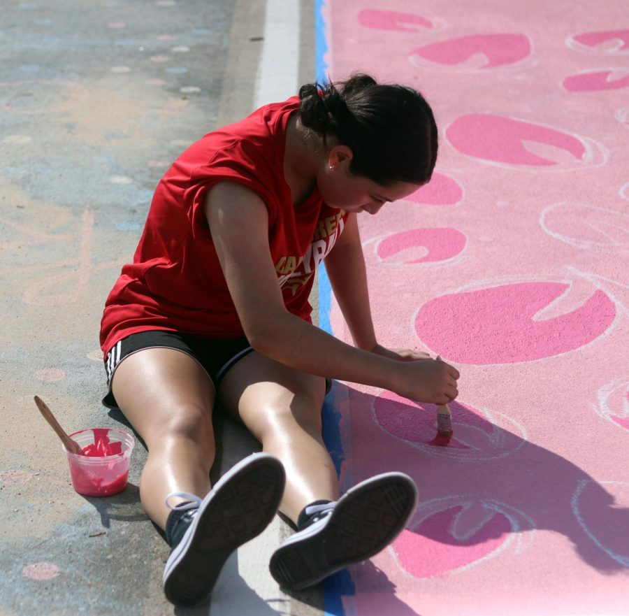 STRAWBERRIES FOR YOU. Senior Amaris Hernandez helps her friend, Senior Kylie Stichler by painting some of the strawberries for Stichlers parking spot. Seniors where welcomed to bring peers to help them paint their parking spots on Sept. 17-18, 2022.