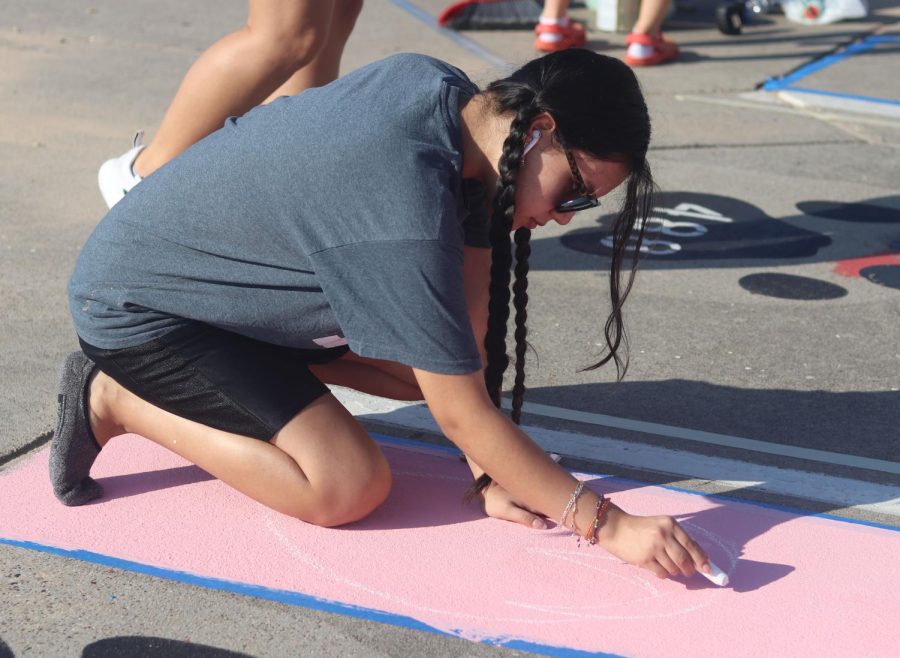 HELPING A FRIEND. Senior Nancy Hernandez helps her friend, Senior Kylie Stichler on her parking spot by drawing strawberries with chalk. Senior had the opportunity to paint their parking spots on Sept 17, 2022 with help of family and friends.