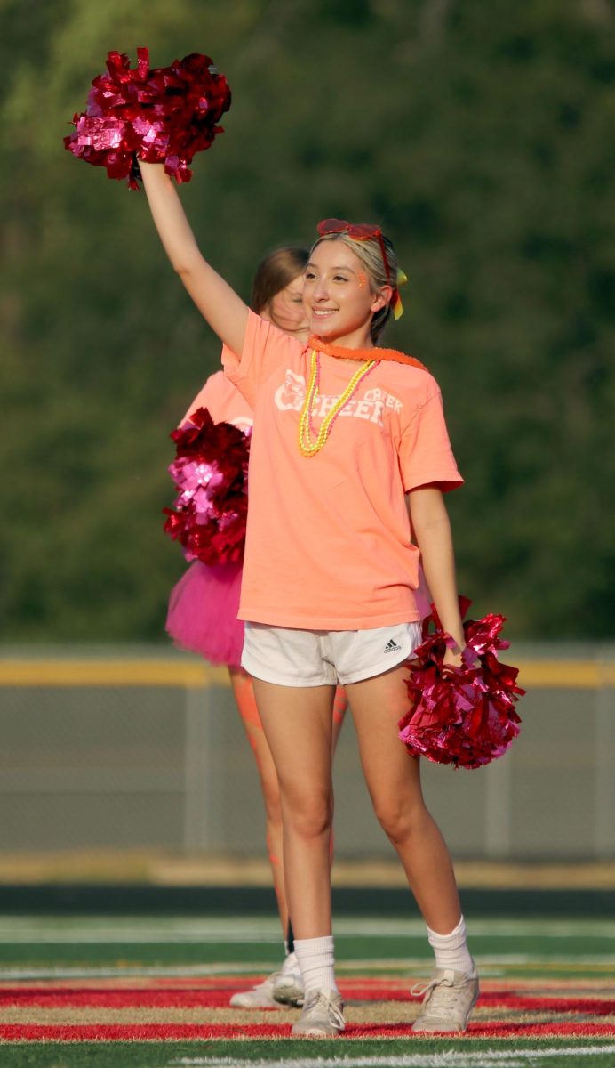 CHEER. Junior Lysette Torres waves towards the cheering crowd at the homecoming parade on Sept. 13, 2023. The cheerleaders made sure to keep the spirit up throughout the parade supporting all organizations that came out to promote themselves. 