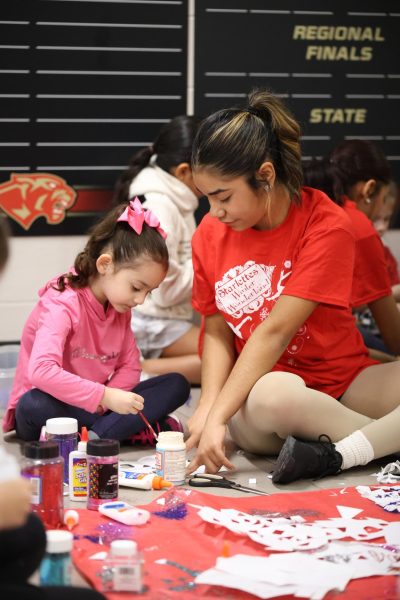 LITTLE ONES. Junior Niria Gaona sits down with a kindergartner to help out with arts and crafts on Dec. 2, 2023. Kids from the kindergarten got to spend time with the starlettes the day after its Winter Wonderland performance. “It was a really nice and amazing experience for me as a starlette because they get to learn new things,” Gaona said. “ I get to be a role model to them and sometimes they look up to us.”
