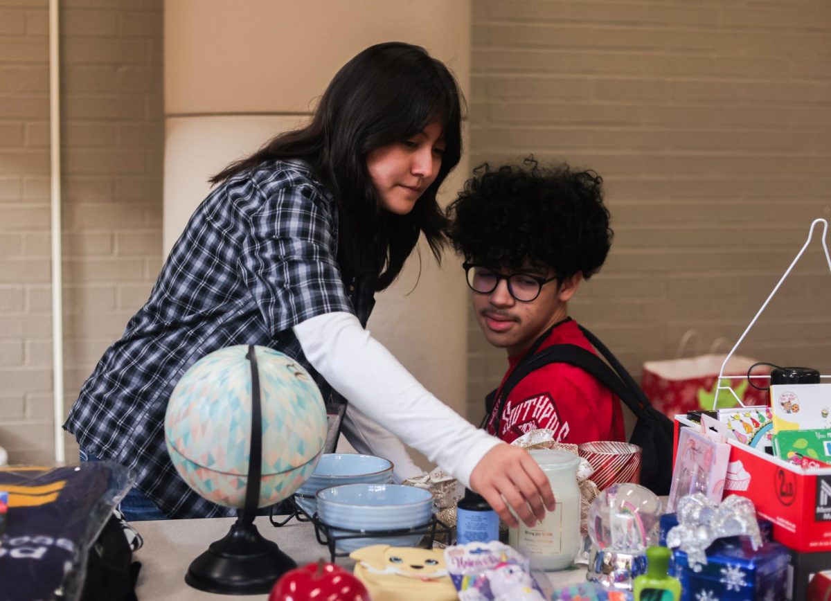 THATS NEAT. Sophomore Josias Rodriguez and another student look through a table of items at the winter thrift store held by STUCO on Dec. 12. All of the items were offered by the student council for free to students; profitable transactions were not made.