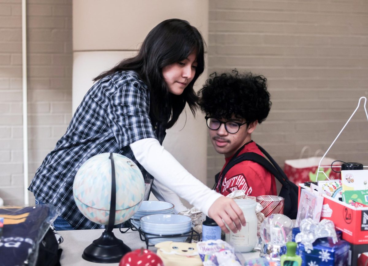 THATS NEAT. Sophomore Josias Rodriguez and another student look through a table of items at the winter thrift store held by STUCO on Dec. 12. All of the items were offered by the student council for free to students; profitable transactions were not made.