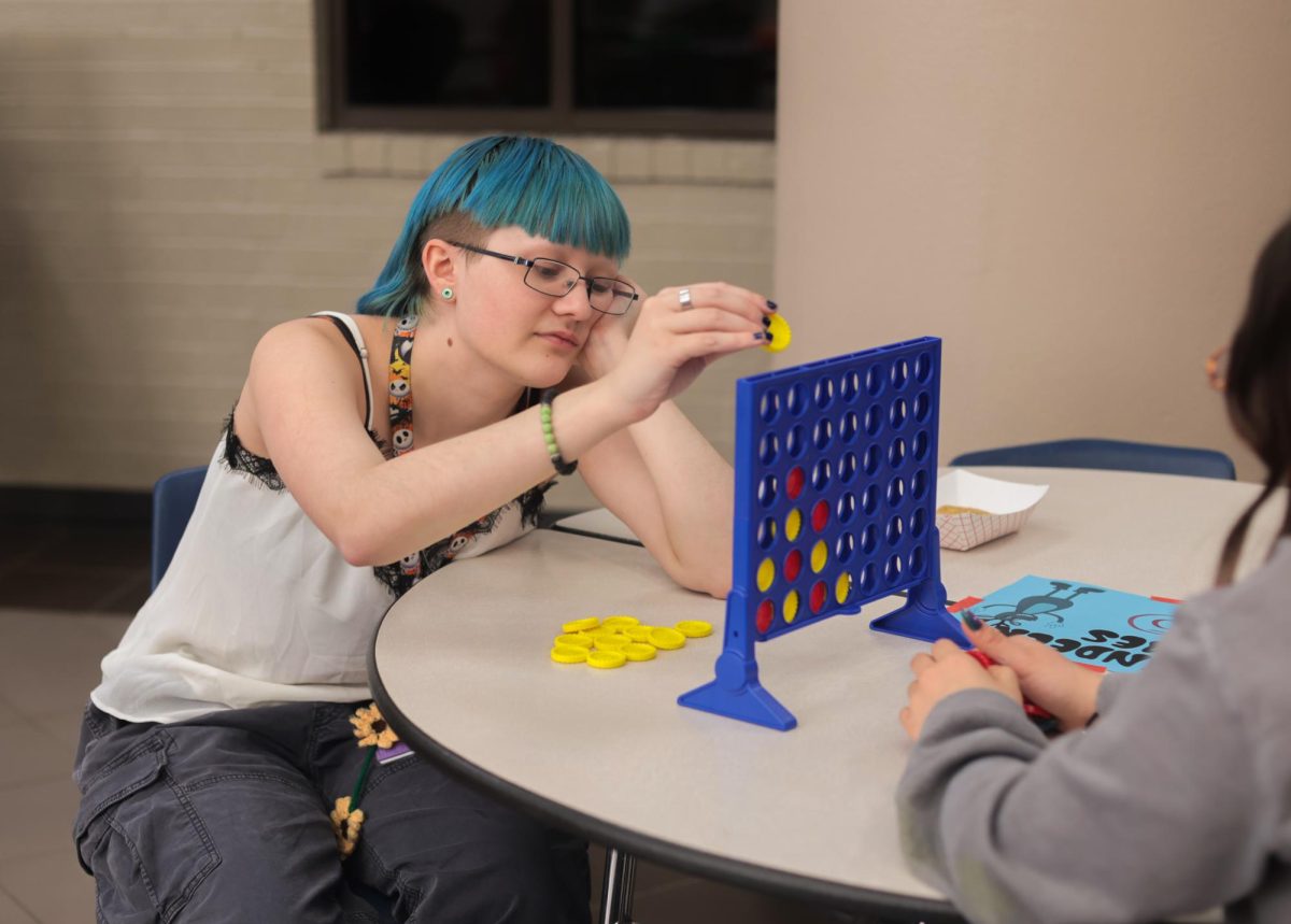 TACTICAL. Junior Mason Rezzoffi sits at a table playing Connect Four against another student at the winter thrift store held by STUCO on Dec. 12. All items at the event were either donated or provided by student council members themselves.