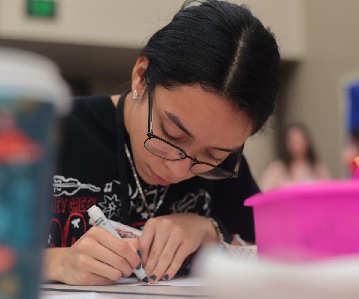 ARTIST. Sophomore Alia Orsoto colors a Christmas color sheet with a marker at the winter thrift store held by STUCO on Dec. 12. Coloring sheets were another activity participating students could take part in aside from the thrifting.