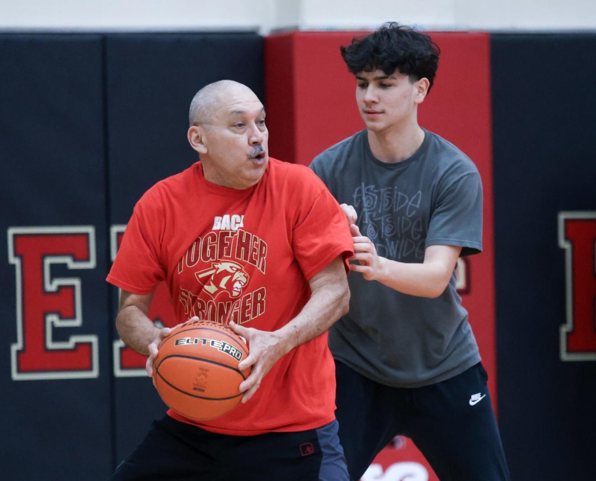 LOVE OF THE SPORT. Spanish teacher Rene Hinojosa holds the basketball while facing a student defender at the Faculty Basketball game on March 3, 2024. Hinojosa annually participates in the Faculty game, one of many examples of his community participation.