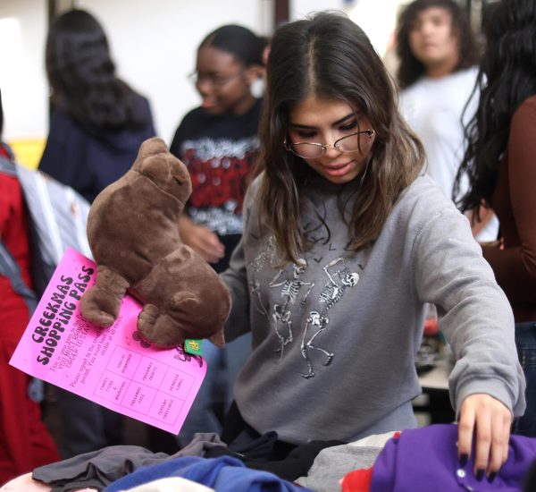 INTERESTING… Junior Alexis Moreno looks through a pile of clothes at the winter thrift store held by STUCO on Dec. 12. Student’s donated various personal items to the council to be sold at the event.