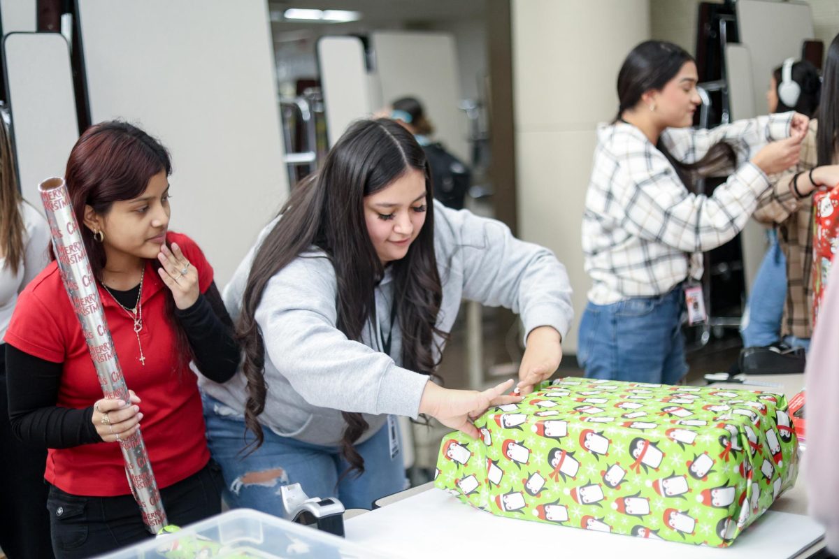 FINISHING TOUCH. A student makes the last fold while wrapping a box at the winter thrift store held by STUCO on Dec. 12