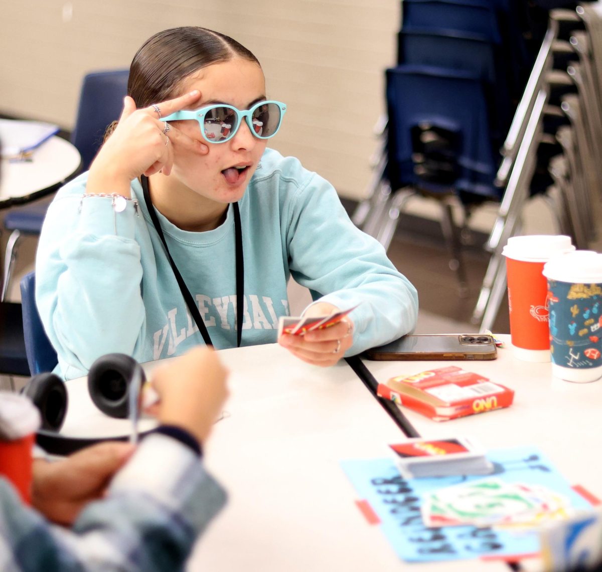 TOO SWAG. Sophomore Zulianette Lorenzo gives a peace sign to her friends across the table while playing UNO at the winter thrift store held by STUCO on Dec. 12.