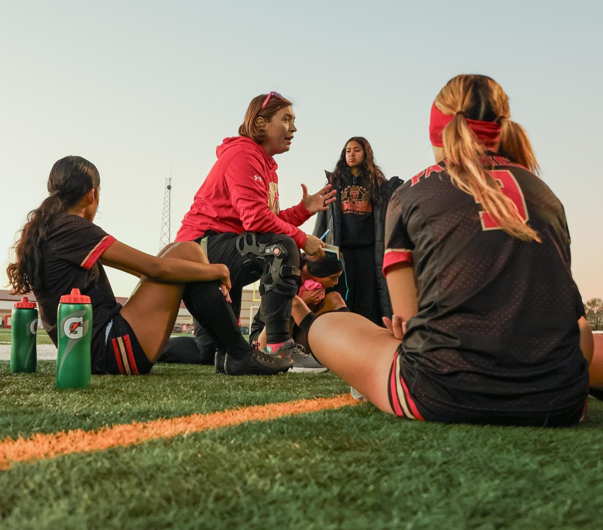 MOMENT OF SUPPORT. Varsity girls soccer head coach Gretchen Kloes kneels down to give words of encouragement to the soccer girls during halftime at the Creek Classic tournament against Clear Falls on Saturday, Jan. 11, 2025.