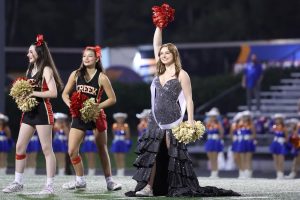 Senior Rylee Peroni stands on a football field in her prom dress and pompoms at the Grand Oaks prom football game on Nov. 11.