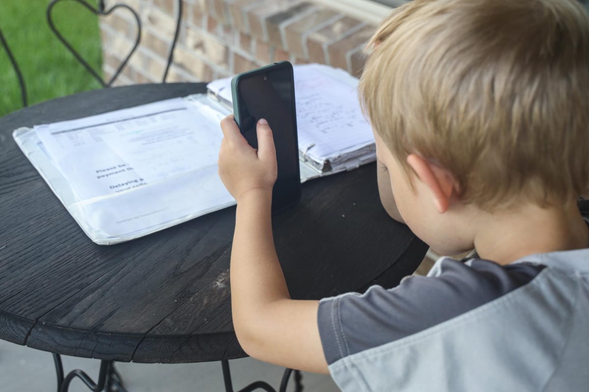 Kindergartener Negan Day plays on his phone June 20 with a math binder in front of him.   