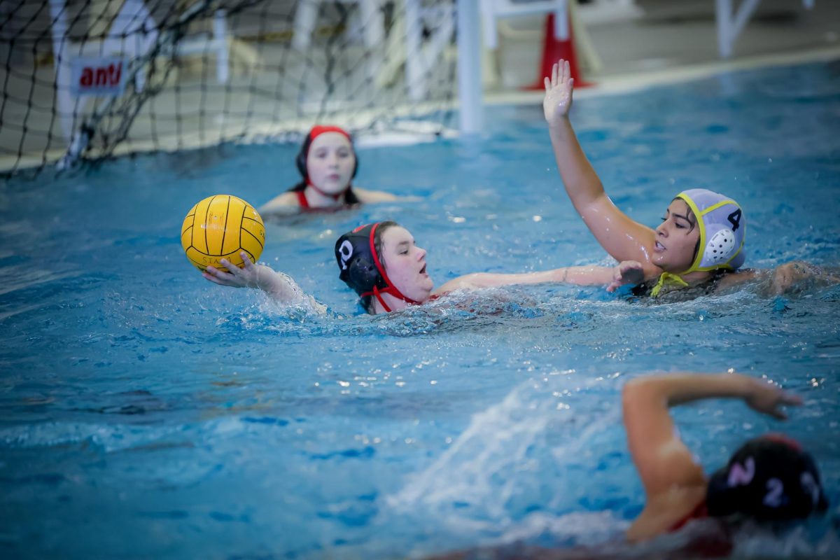 PASS. At the Aldine Tournament for water polo on Friday, Aug. 15, Sky Robinson (12) prepares to pass while being blocked by No. 4. Robinson played all three games without subbing out. “I’m proud of myself for being able to play for so long and getting the number of passes that I did, and I’m also proud of our team for getting the win,” Robinson said.