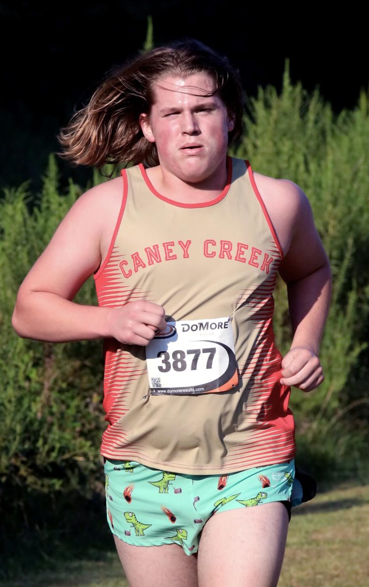 DINO DASH. Senior Jaydan Zubik bolts down the track in dino shorts on Sep. 13 at the Dayton Invitational Meet. “I loved the shorts because they just had dinosaurs on them,” Zubik said. “They boosted my confidence during the run."