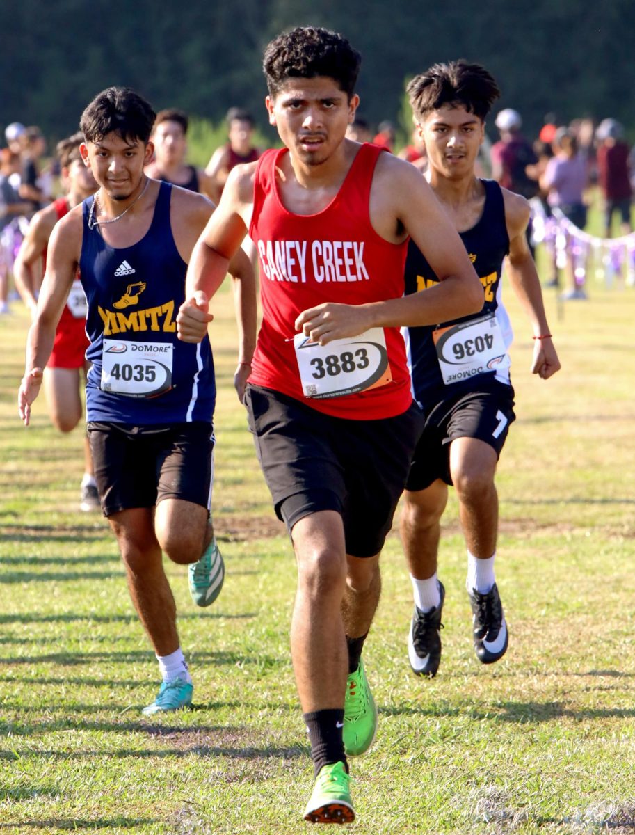 QUICK PURSUIT. Junior Eduardo Arcile sprints towards the finish line with two runners on his tail on Sep. 13 at the Dayton Invitational Meet. Arcile pushes forward despite the pressure behind him.