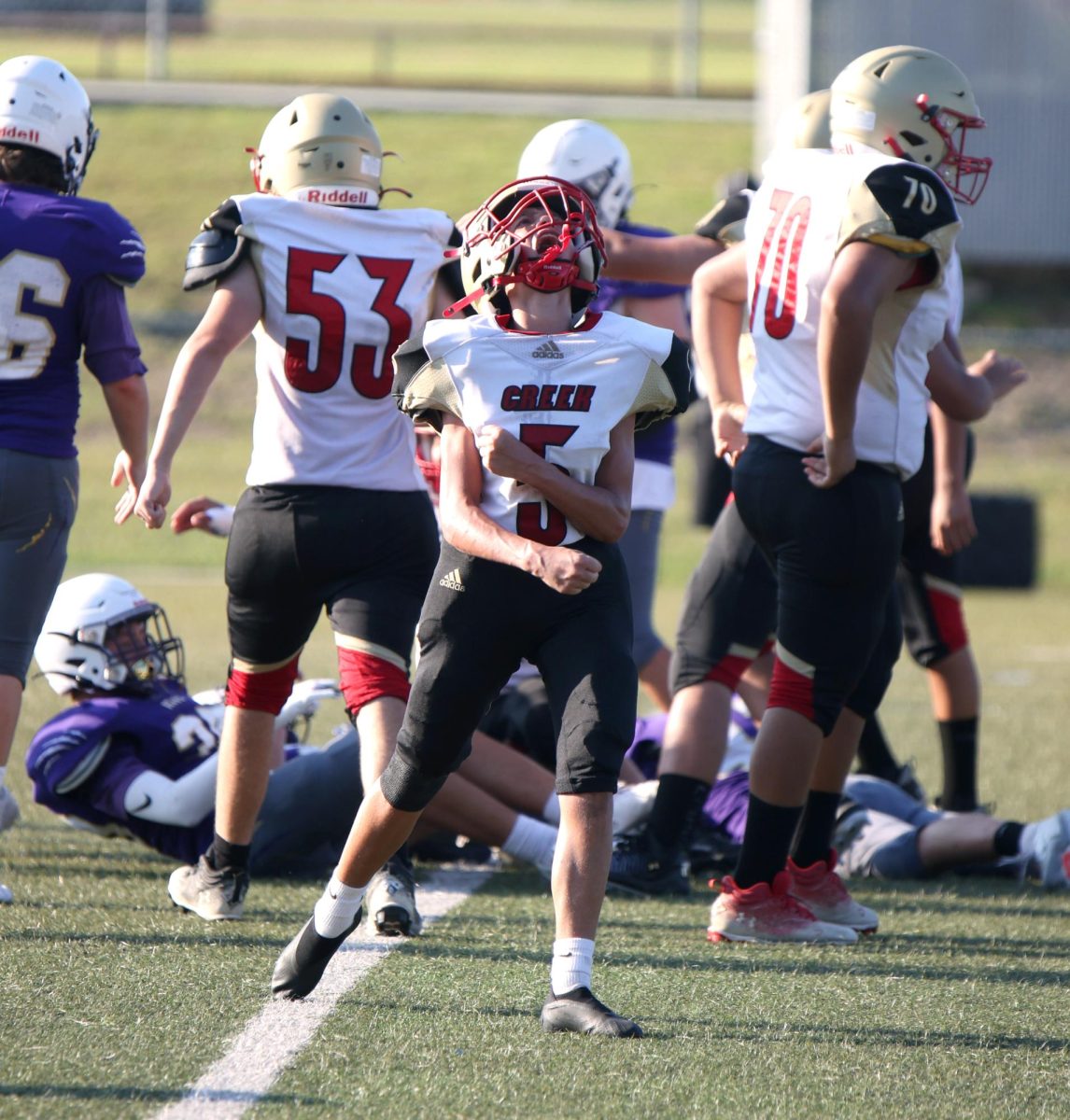 VICTORY STRIDE. Freshman Treghan Earley screams in the air after getting a tackle on Aug. 4, 2025. Earley tackles the opponents quarterback during a play.