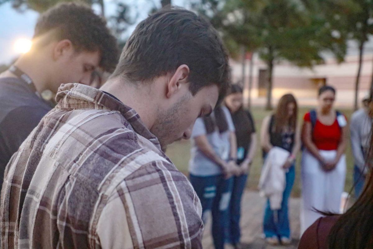 Senior Timothy Williams bows his head in prayer while participating in the annual group prayer circled around the flag pole Sept. 24. Once a year the Fellowship of Christian Athletes, run by sponsor Mark Kovach, gathers to pray for the wellbeing of all Texas schools. “You get to see others who you see in the hallways on a daily basis and didn’t know you shared the same beliefs and connect with,” Williams said. “It creates comfort that you're not alone in the school and there’s others out there who wish to make the school and world a better place through their beliefs and not be afraid to do it.”