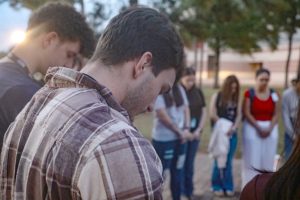Senior Timothy Williams bows his head in prayer while participating in the annual group prayer circled around the flag pole Sept. 24. Once a year the Fellowship of Christian Athletes, run by sponsor Mark Kovach, gathers to pray for the wellbeing of all Texas schools. “You get to see others who you see in the hallways on a daily basis and didn’t know you shared the same beliefs and connect with,” Williams said. “It creates comfort that you're not alone in the school and there’s others out there who wish to make the school and world a better place through their beliefs and not be afraid to do it.”