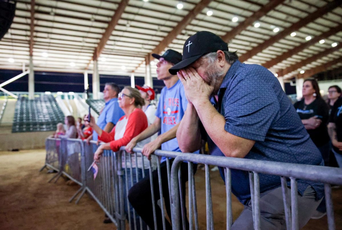 IT'S REAL. Hatted audience member covers his face as a Charlie Kirk video collage plays on the stage projector of the Montgomery Fairgrounds stadium during the Kirk Memorial Service Sept. 30 The member periodically cried through the video, covering his face during a clip of Kirk’s family.