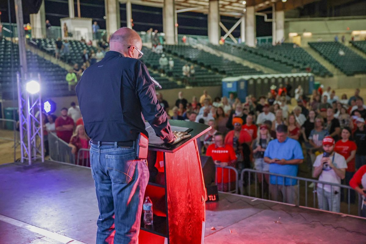 LISTEN WHEN HE SPEAKS. Judge Wayne Mack stands at the stage podium of the Montgomery Fairgrounds stadium, in front of the audience. Wayne looked down at his speech, memorizing his prayer minutes before delivering.