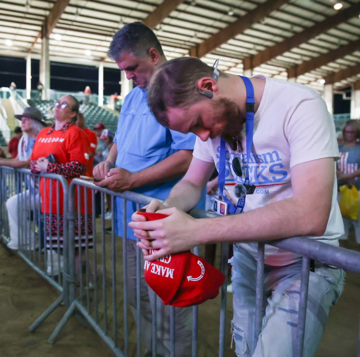 HATS OFF. Audience member of the Sept. 30 Charlie Kirk memorial service bows his head in prayer grasping a MAGA hat, while leaning on the stage barriers of the Fairgrounds stadium. Judge Wayne Mack led the prayer calling to honor Kirk’s legacy.