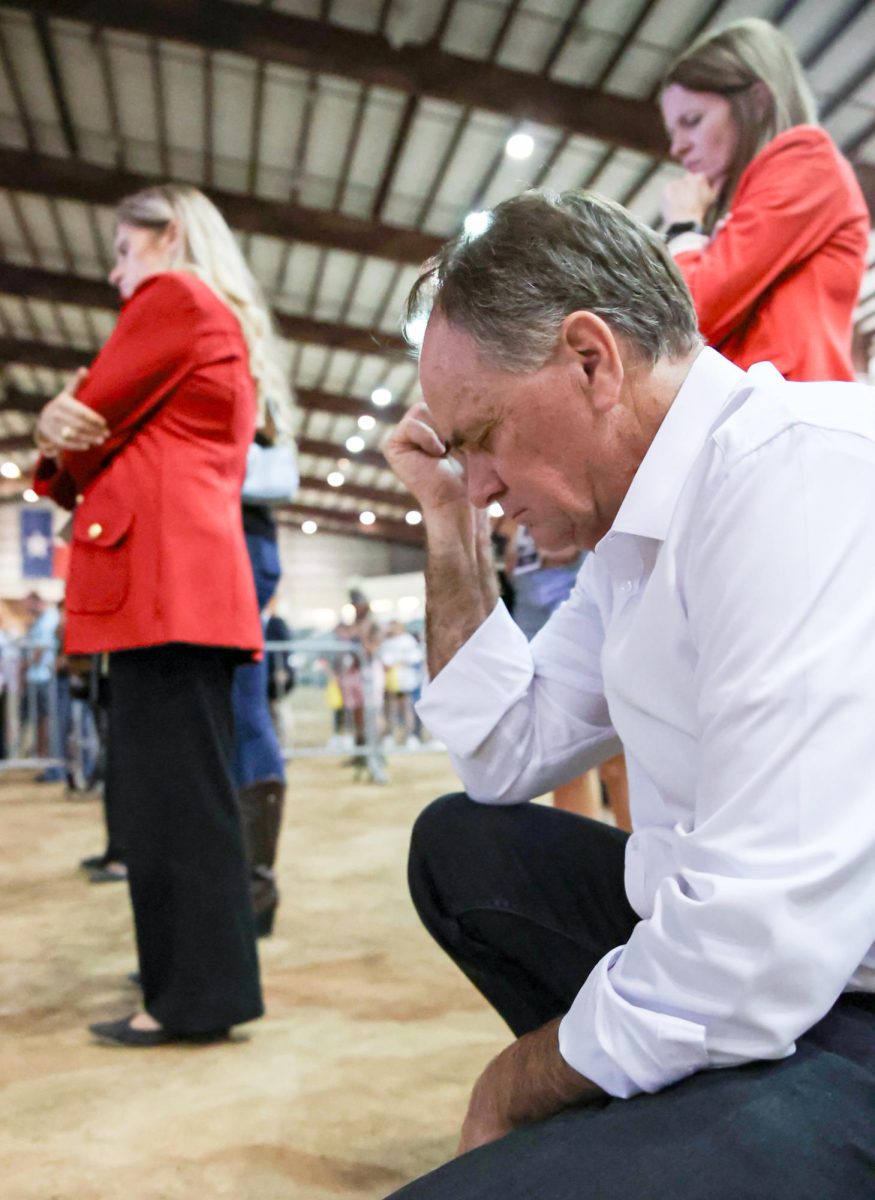 FALLEN. Rep. Steve Toth (R-Conroe) kneels in prayer from backstage of the Charlie Kirk memorial service at the Montgomery Fairground Sept. 30. County Judge Wayne Mack closed the service in prayer.