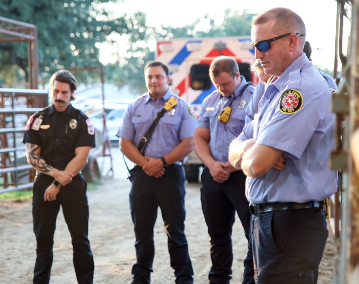 HERE FOR YOU. A row of first responders bow their head as the pledge of allegiance plays at the beginning of the Montgomery Fairground Charlie Kirk memorial service Sept. 30. Coordinators stationed first responders directly behind the stage in the case of a speaker facing injury. Officers also lined the stadium pit.