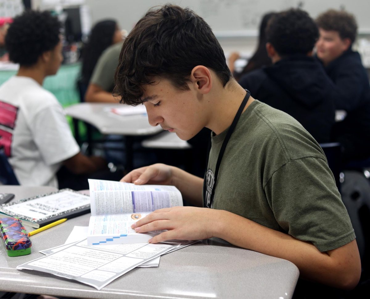 SAMPLE TEXT. Freshman Mason Sample looks through a textbook while studying for a worksheet in his English 1 class on Sept. 9. Students selected their own book to study for the paper.
