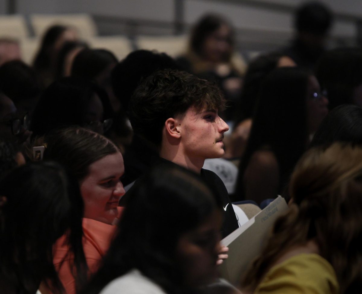 LISTENING EAR. Junior Rayden Peroni listening as the National English Honors Society leaders speak at the podium before new inductees walk up to receive their certificates on Sept. 9, 2025. “I feel like this is a really good thing for me as an athlete. Getting to meet new people, see the world more, and how they view things feels really good.” Peroni said.