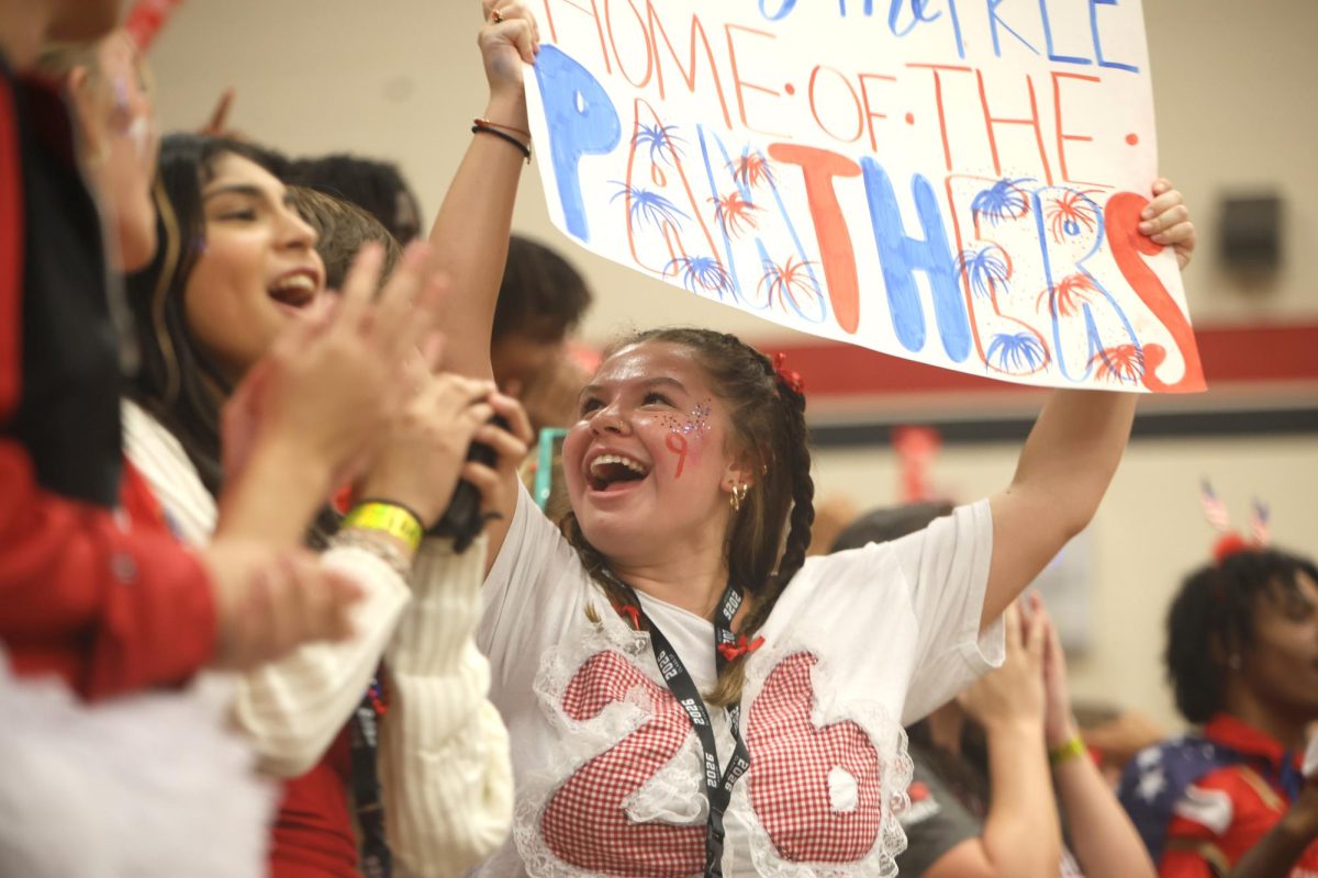 ROOP’S RALLY. Senior Mayah Roop looks back at her friends to make sure they’re also cheering for their side at the pep rally on Sept 12, 2025. Roop holds a sign that she made for the spirit day pep rally. “I love to make signs to show my school spirit and pride,” Roop said. “Being on the senior side at pep rallies is so bittersweet, it’s a feeling so hard to describe, knowing that this is my last year in this gym cheering with all my friends and classmates.”