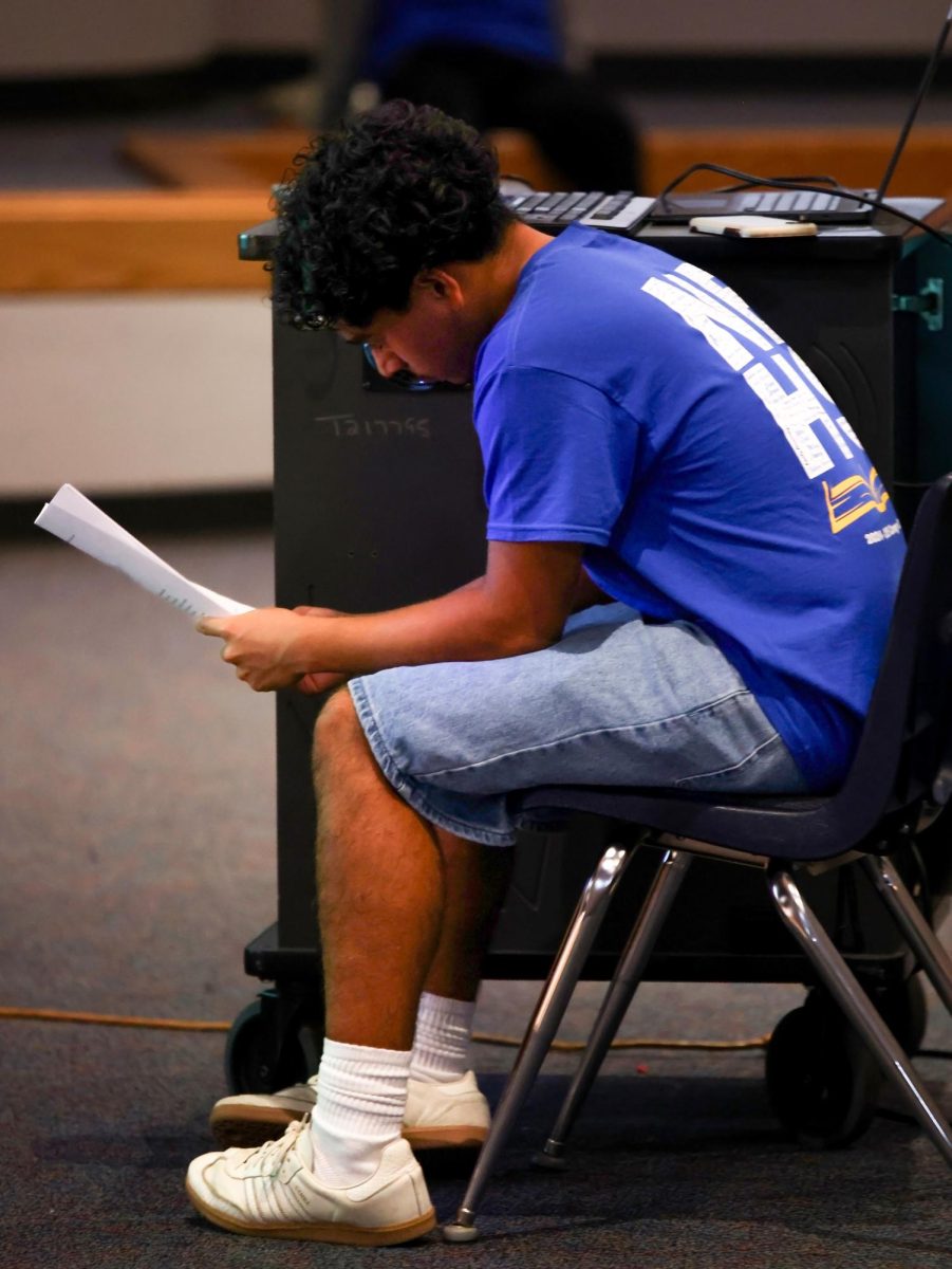 EXCITEMENT. Senior Eduardo Torres watching the ceremony and reading his name sheet at the Nehs Induction ceremony September 9. Torres was proud and excited for the new upcoming inductees.
