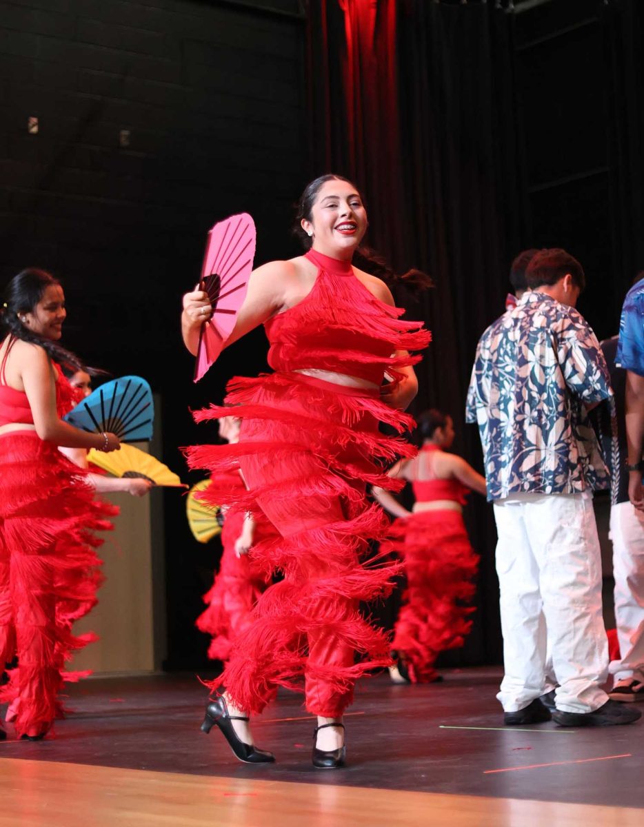 TWIRL TO THE BEAT. Senior Jacqueline Arteaga twirling on stage, flapping her fan while dancing at Moorhead for the Hispanic Heritage Month show on Tuesday, Oct. 14, 2025.