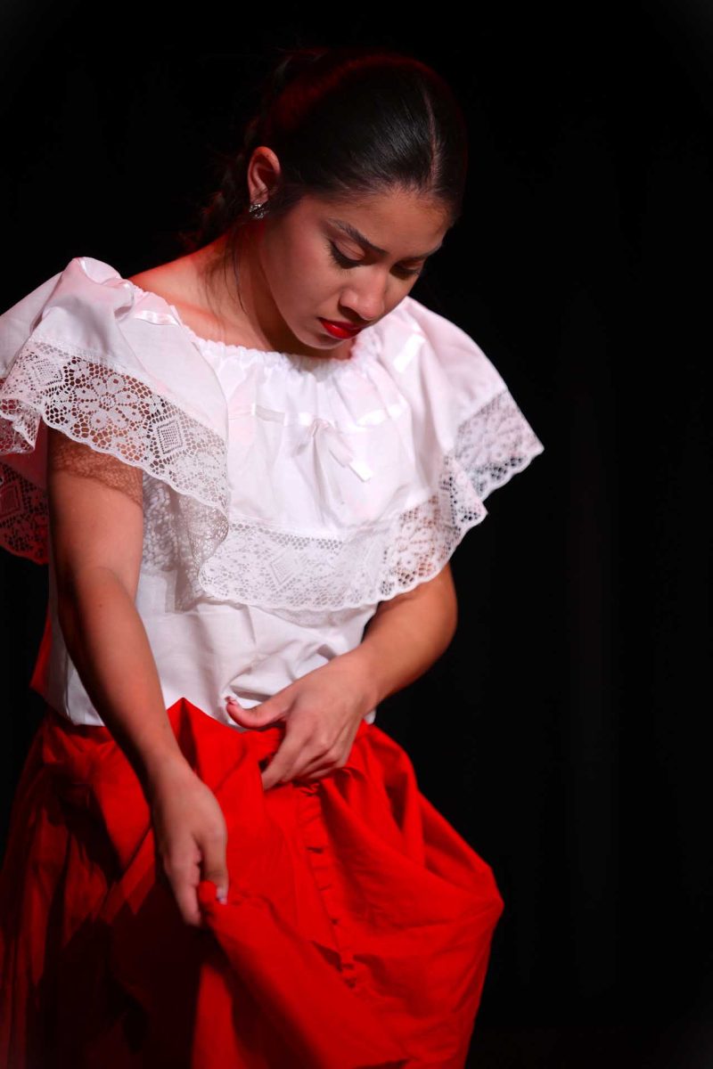 POISE IN PREPARATION. Senior Stacy Balderas adjusts her folklórico skirt before her performance at Moorhead Junior High School begins on Tuesday, Oct. 14, 2025. As a four-year member of the school’s panteras en fuego dance team, Balderas helped lead the group through its final showcase of the year, celebrating months of practice and cultural pride. “We did the best to our abilities on stage,” Balderas said. “We just have bonds throughout the team that make the dance better.”