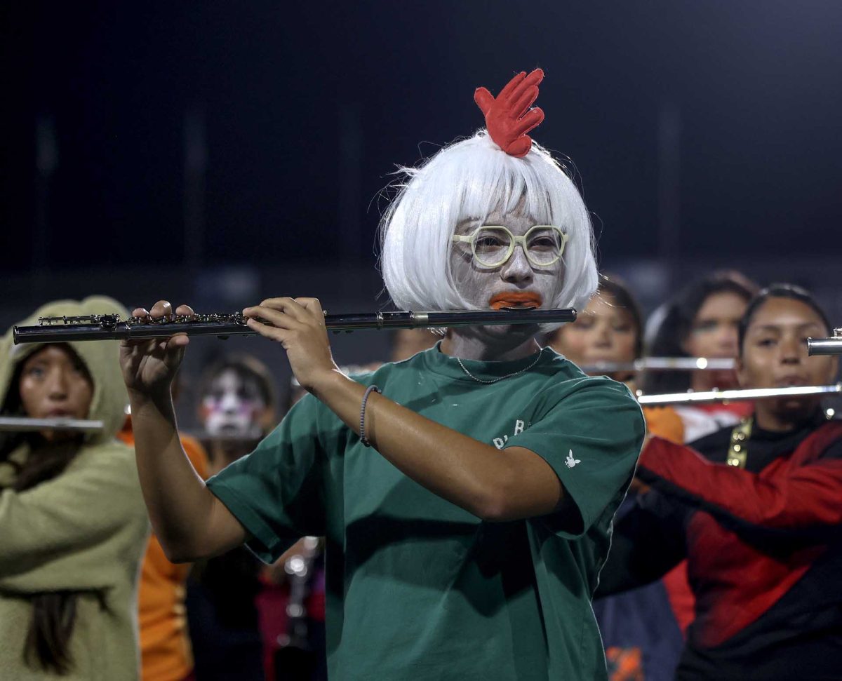 HALFTIME HATCH. Junior Josias Godinez plays the flute during halftime during the Halloween football game against Oak Ridge. Godinez dressed up as chicken little for Halloween, setting the mood for the night.
