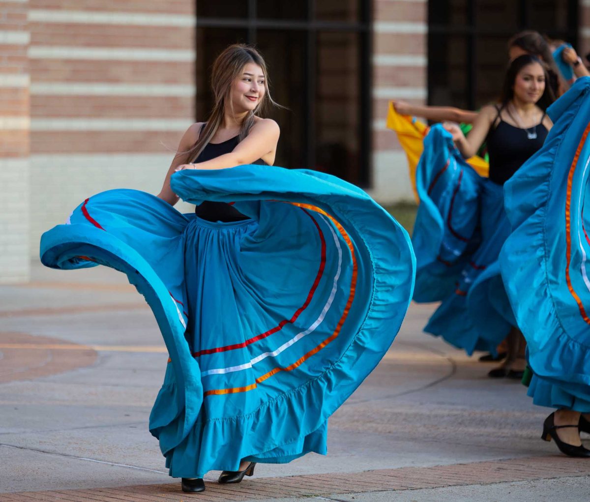 SHOWSTOPPER. Senior Aryany Lemus Ortega smiles at the other dancers as they begin to form a line while she swings her skirt during the world dance class’s performance on Oct. 14, 2025.